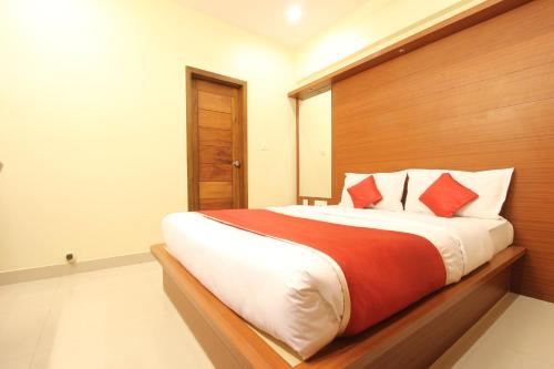 a bedroom with a large bed with red and white pillows at The Grand Inn Mysore in Mysore