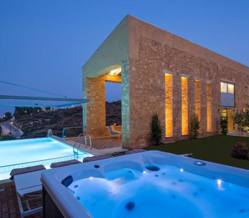 a bath tub in front of a house with a swimming pool at Olea Villas - Infinity Pool, Hot Tub, Sea Views in Marathi