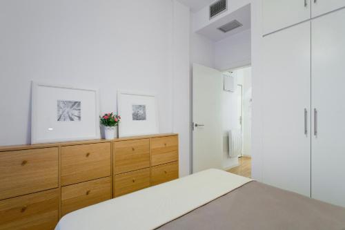 マドリードにあるGran Via Apartment by Flatsweethomeの白い壁のベッドルーム(木製ドレッサー付)