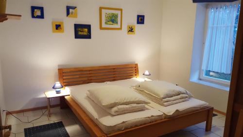 - une chambre dotée d'un lit avec des oreillers et des photos sur le mur dans l'établissement Haus Seeblick Insel Rügen, à Lietzow