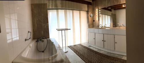 une grande salle de bain avec une baignoire et un lavabo dans l'établissement La ferme de Pouzatel proche Bonaguil, à Fumel