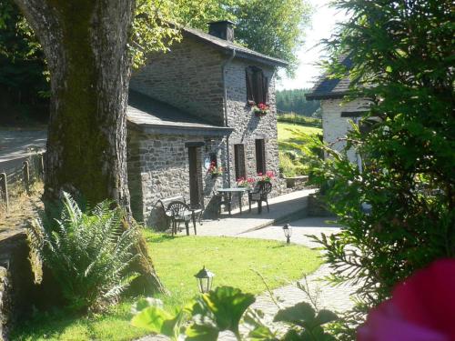 a stone house with a table and chairs in a yard at Attractive Cottage in Baillamont with Terrace in Bièvre