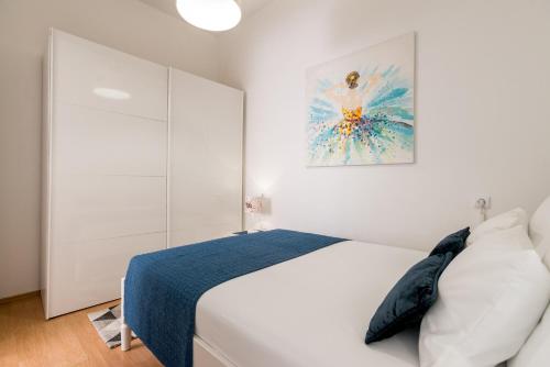 a white bedroom with a bed and a painting on the wall at Apartment Kala in Split