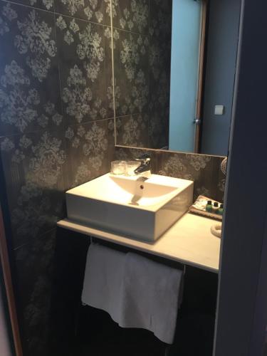 
a white sink sitting under a mirror in a bathroom at Hotel Patilla Ciudad de Requena in Requena
