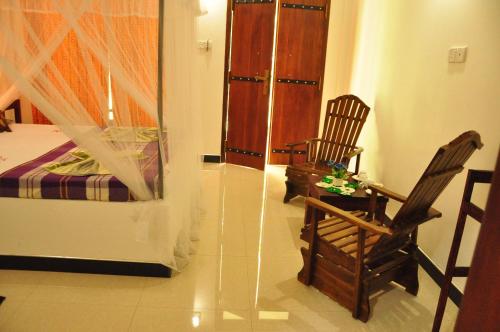 a bedroom with a bed and two rocking chairs at sigiriya flower guest in Sigiriya