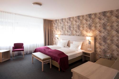 Pokój hotelowy z łóżkiem i krzesłem w obiekcie Hotel Senator München w Monachium