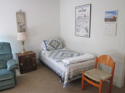 a small bedroom with a bed and a chair at Dodgeton Creek Inn in Cuchara