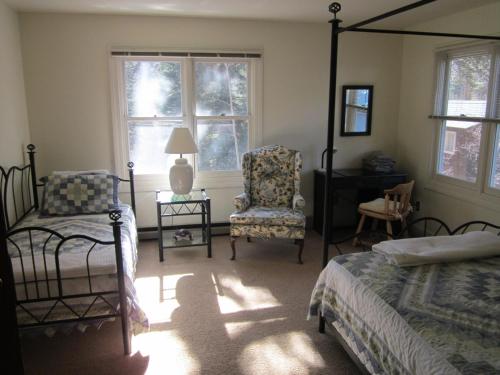 a bedroom with a bed and a chair and windows at Dodgeton Creek Inn in Cuchara