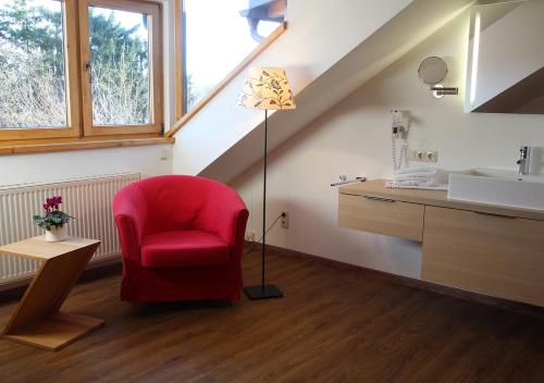 a red chair in a bathroom with a sink and a lamp at Sporerhof in Murnau am Staffelsee