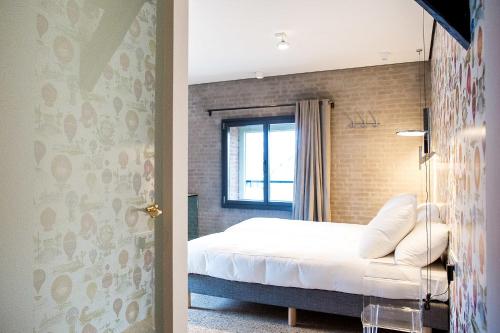 a bedroom with a bed and a brick wall at Hotel Napoleonschuur in Amerongen