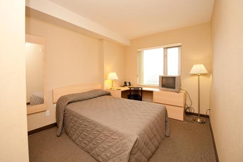 Dormitorio con cama, escritorio y TV en Residence & Conference Centre - Kamloops, en Kamloops