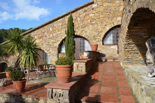 a stone building with potted plants on a patio at Hotel Galena Mas Comangau in Begur