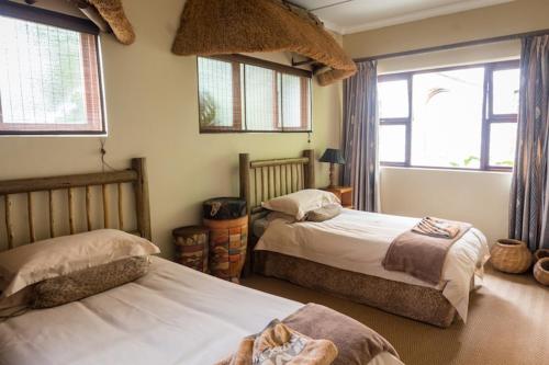 two beds in a room with two windows at Oribi Gorge Guest Farm in Glendale