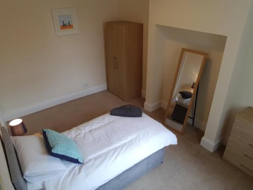 a bedroom with a white bed and a mirror at Tunstall Serviced Home in Sunderland