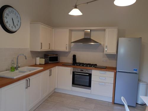a kitchen with white cabinets and a clock on the wall at Tunstall Serviced Home in Sunderland