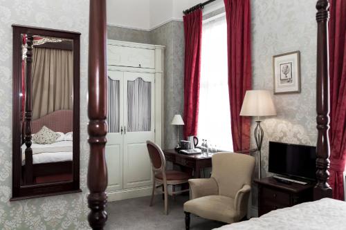 a hotel room with a bed, chair, mirror and a window at Butlers Townhouse in Dublin