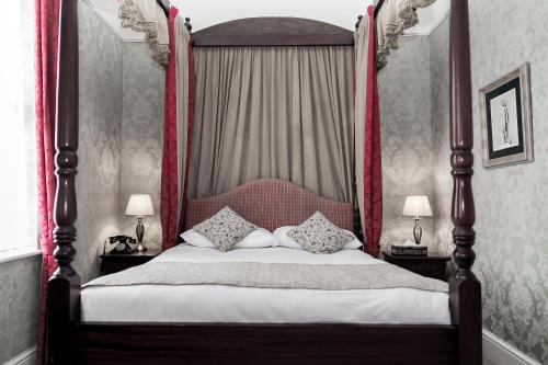 a bedroom with a canopy bed with pillows on it at Butlers Townhouse in Dublin