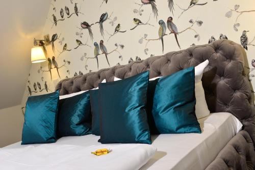 a bedroom with a couch with blue pillows and birds on the wall at Hotel Domstern in Cologne