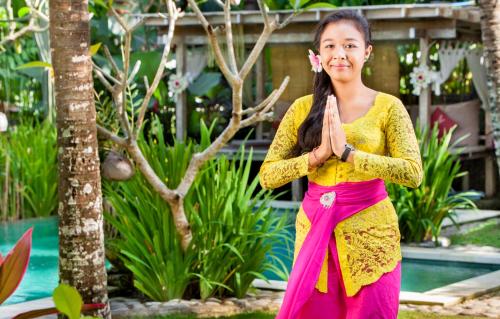 una mujer con un vestido amarillo y rosa haciendo yoga en Arimba at Bisma, en Ubud