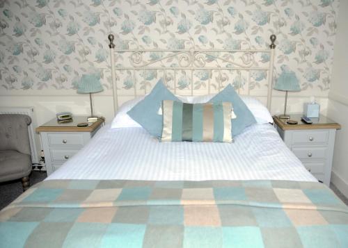 a bedroom with a white bed with blue and white pillows at Douglas House in Castle Douglas