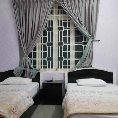 a bedroom with two beds and a large window at Bac Huong Hotel in Kon Tum