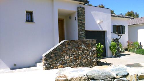 a house with a stone wall and a gate at A Sulana Chambre d'hôtes in Valle-di-Campoloro