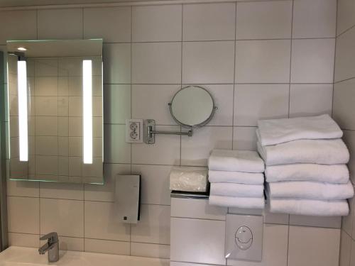 a bathroom with a stack of towels and a mirror at Pilot Airport Hotel in Vantaa