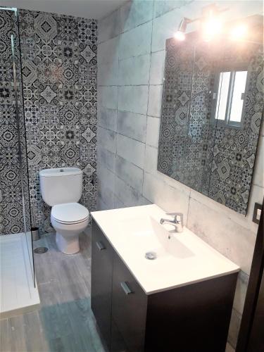 a bathroom with a toilet and a sink and a mirror at Apartamentos Sol Compañia in Úbeda