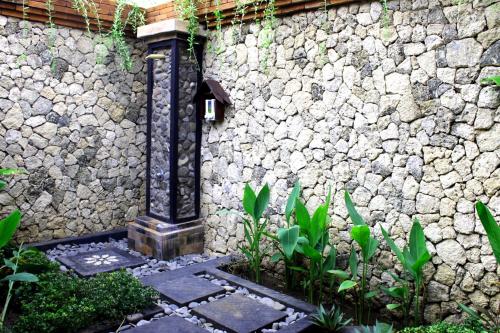 a stone wall with a bird feeder on it at Mans Cottages & Spa in Pemuteran