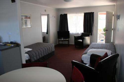 a hotel room with two beds and a chair at Burgundy Rose Motel in Whangarei