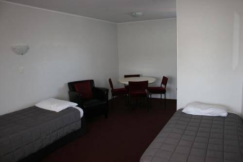 a room with two beds and a table and chairs at Burgundy Rose Motel in Whangarei