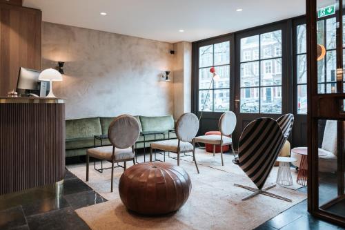 a lobby with chairs and a couch and windows at The Times Hotel in Amsterdam