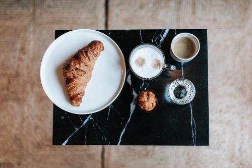 a plate with a piece of bread and a cup of coffee at The Times Hotel in Amsterdam