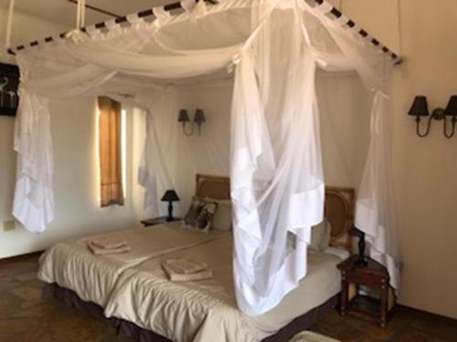 a bedroom with a canopy bed with white drapes at Halala Africa Lodge - Eagle Rock Lodge in Malabar
