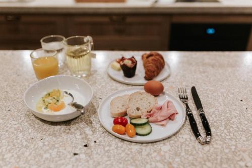 two plates of food on a table with eggs and meat at The Times Hotel in Amsterdam