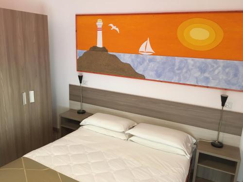 una camera con un letto e un dipinto di un faro di Hotel Corallo a Fregene