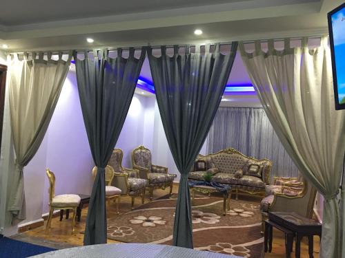 een kamer met gordijnen en stoelen en een televisie bij Private Family Apartment in Dokki in Caïro