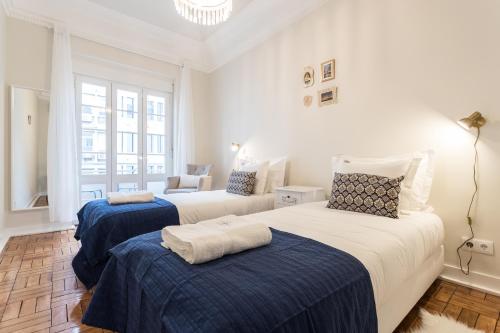 sypialnia z 2 łóżkami z niebieską i białą pościelą w obiekcie Cruz Apartments w Lizbonie