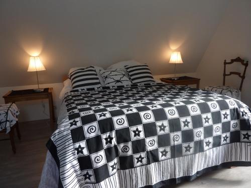 a bedroom with a black and white bed with pillows at B&B La Baronniére in Cordebugle