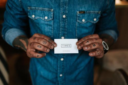 a man with tattoos on his hands holding a piece of paper at The Times Hotel in Amsterdam