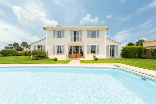 une grande piscine devant une maison dans l'établissement Madame Vacances Les Villas de Fontenelles, à LʼAiguillon-sur-Vie