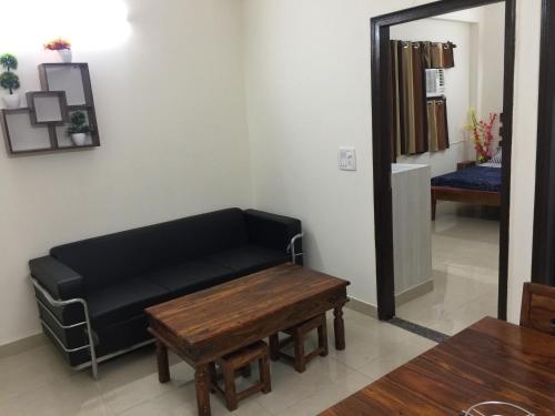 a living room with a black couch and a table at The Raveesh E24 - 2BHK Serviced Apartment in New Delhi