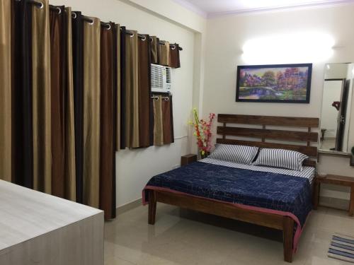 a bedroom with a bed with blue sheets and curtains at The Raveesh E24 - 2BHK Serviced Apartment in New Delhi