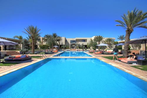 a pool at a resort with palm trees and umbrellas at Sirayane Boutique Hotel & Spa Marrakech in Marrakesh