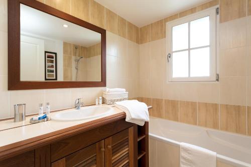 y baño con lavabo, espejo y bañera. en Madame Vacances Les Villas de Fontenelles, en LʼAiguillon-sur-Vie