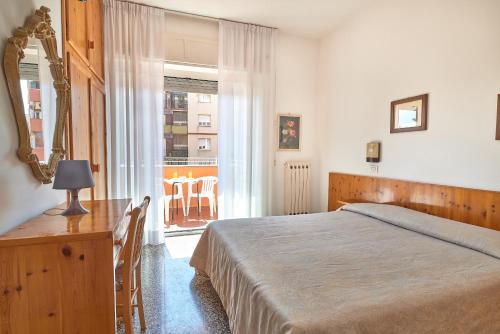 una camera con letto, scrivania e finestra di Albergo Natalina a Finale Ligure