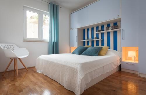 um quarto com uma cama branca e uma cadeira branca em Relax Makarska em Makarska