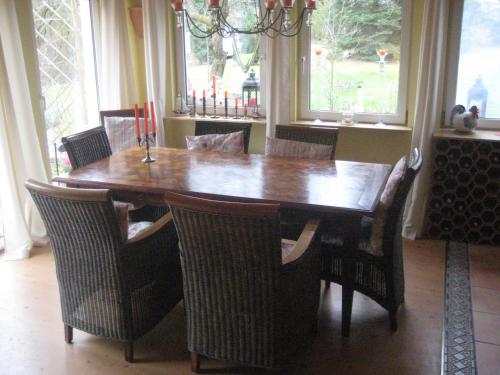 mesa de comedor y sillas con mesa de madera y ventanas en Ferienhaus bei Berlin en Falkensee