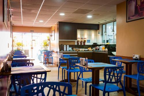 a restaurant with blue chairs and tables and a kitchen at Espaço 345 Hotel in Paulínia