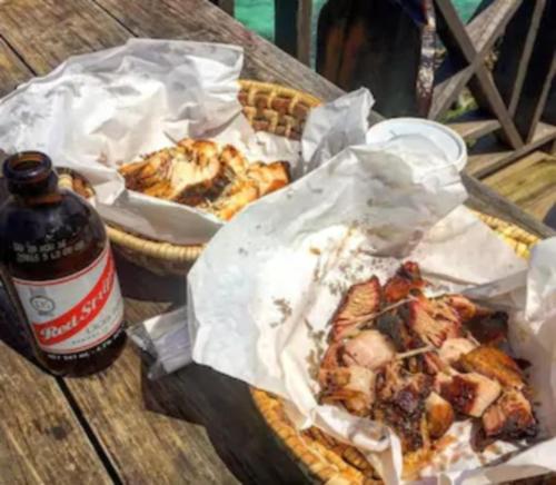 a table with two baskets of food and a bottle of beer at Artist Place Kensington 2BR New Kingston in New Kingston